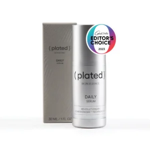 A silver bottle of Plated Skin Science Daily Serum stands before its matching box, next to the Detoxifying Mask for a full routine. A circular "Editor’s Choice 2023" badge appears on the upper right side of the bottle.