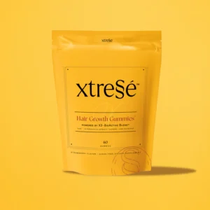 A yellow pouch labeled xtresé Hair Growth Gummies stands upright on a yellow background, containing 60 strawberry-flavored, sugar-free gummies for hair growth. Next to it is the Detoxifying Mask for a complete beauty routine.