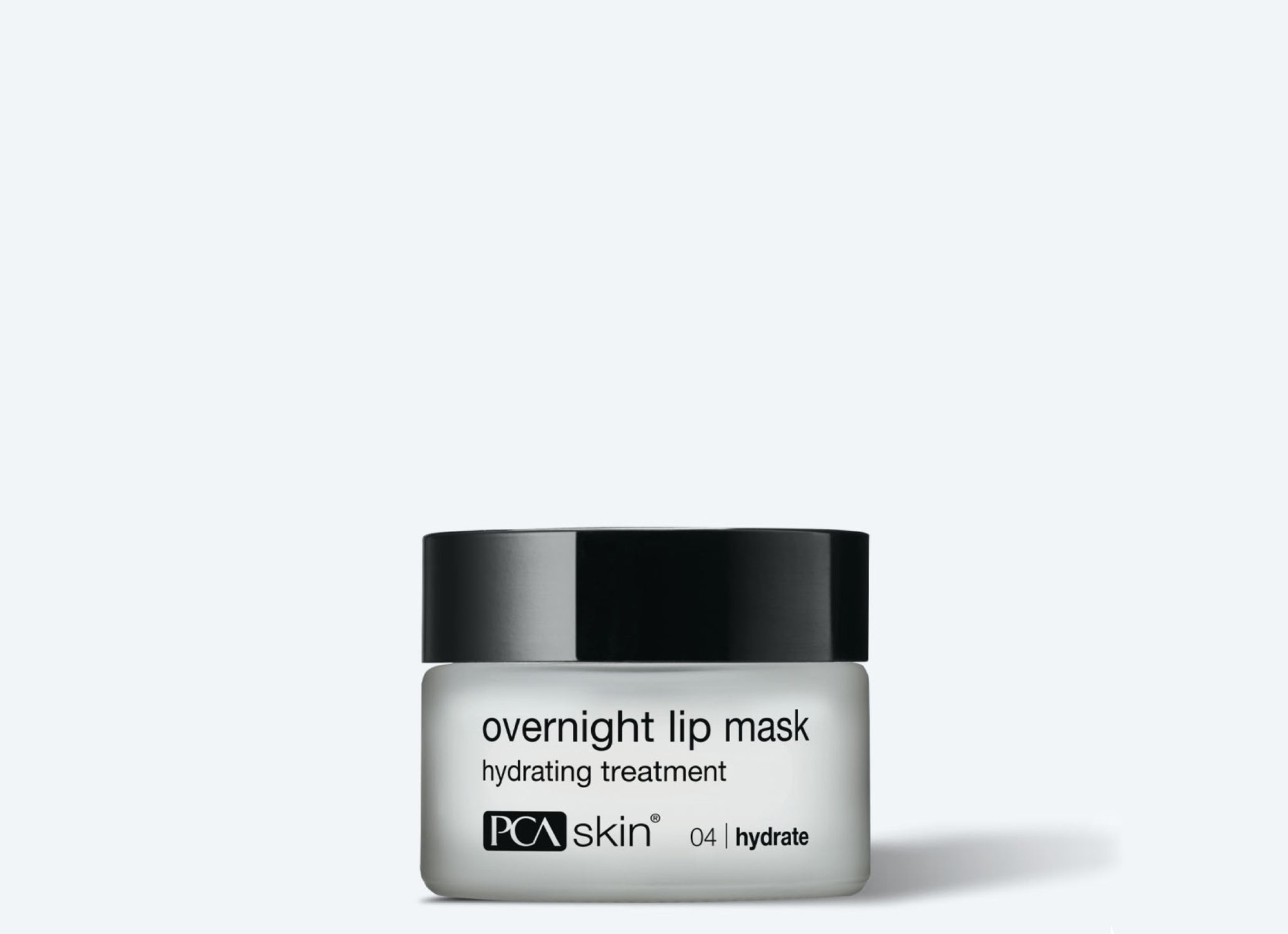 A small jar of Detoxifying Mask with a black lid and white label featuring black text is shown against a light gray background, resembling a mini face mask or detoxifying treatment.