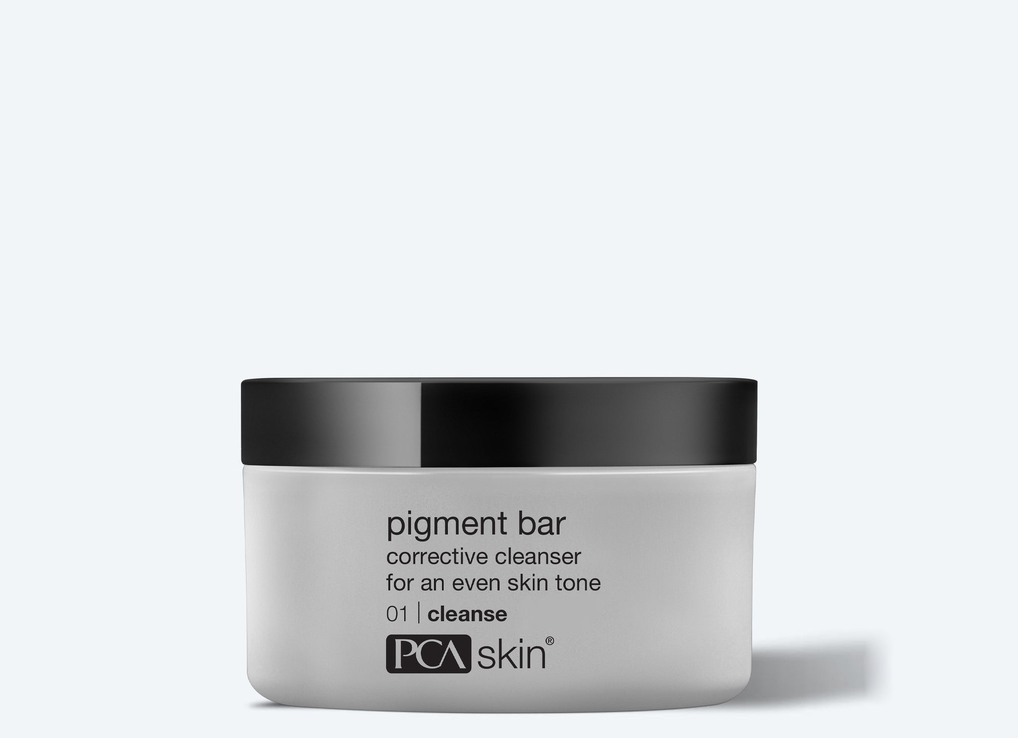 A white jar with a black lid labeled "pigment bar corrective cleanser for an even skin tone 01 cleanse" from PCA Skin sits on a light gray background—ideal prep before applying the Detoxifying Mask.
